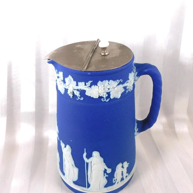 This is a dark blue Wedgwood Jasperware trojan jug or pitcher with a metal cap that may be used for coffee, tea, or other...
