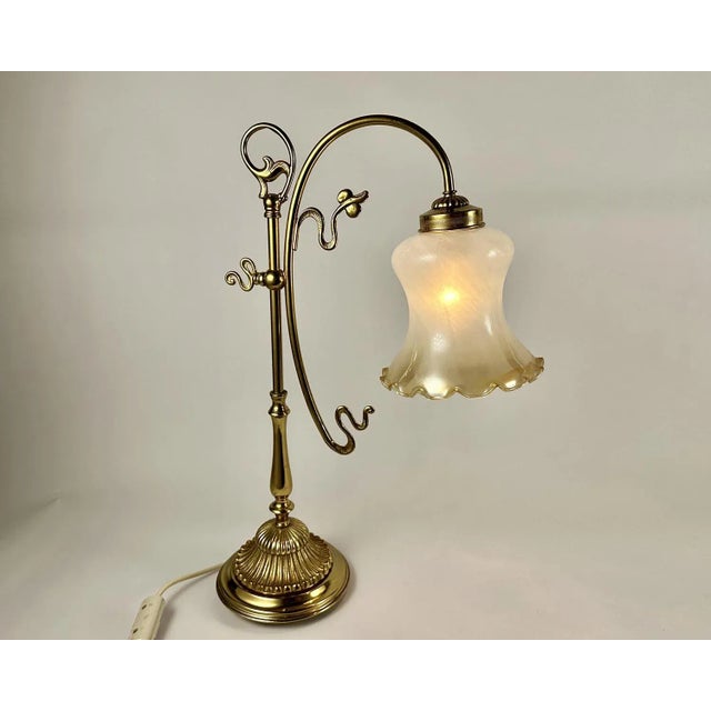 Pair of vintage table lamps with a frosted glass bell-shaped lampshade on an elegant, smoothly curved brass leg. The...