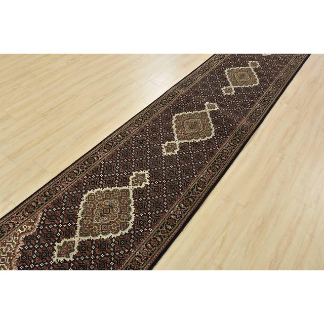 A traditional Tabriz Mahi runner hand-knotted with an all-wool pile on a cotton foundation. This finely woven oriental rug...