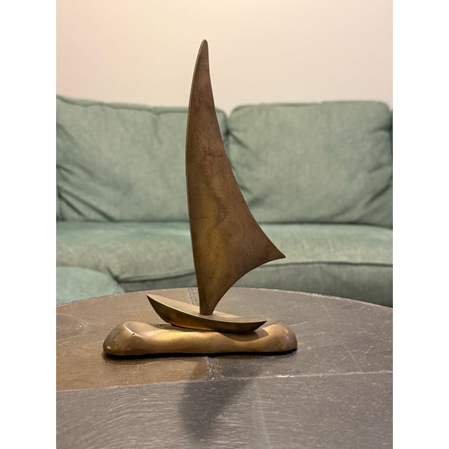 Beautiful vintage solid brass sailboat sculpture featuring an elegant, sweeping sail and sleek, minimalist design. This...