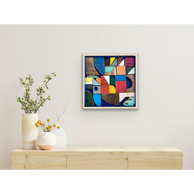 "Color Build: Summer Sail in Royal Blue" is 16x16x1" reclaimed wood and acrylic paint nestled in a maple panel frame. The...