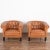Pair, brown leather barrel back arm chairs with contrasting black hard wood legs. Upholstered club chairs in button-tufted...