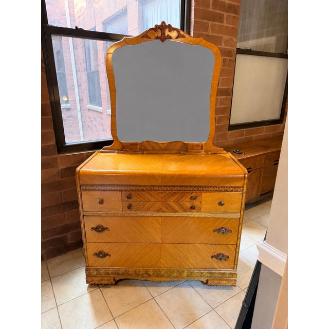 A beautifully crafted late 1930s Art Deco dresser with its original matching mirror, distinguished by book-matched...