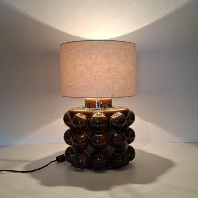 The Porta Romana table lamp captivates with its textured surface of glazed ceramic in a deep brown tone. Height: 33.5 cm...