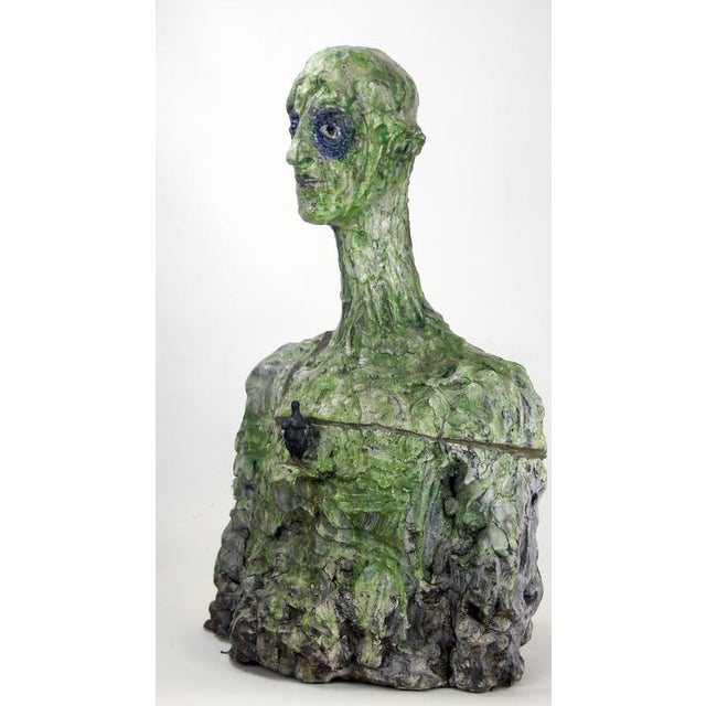This figurative ceramic and bronze bust sculpture highlights a fragmented surface that evokes repair, continuity and...