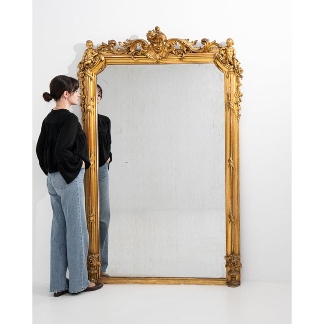 Here is a mirror, its gold gilt ornate frame with figural crest the first thing to catch the eye. It was made in France...