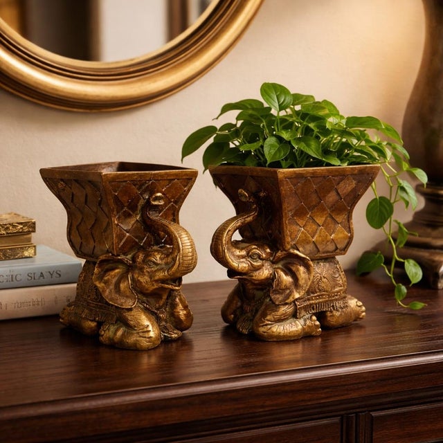A sculptural pair of Hollywood Regency elephant cachepots with rich antiqued gold finish and ornate detailing. Perfect for...