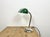 This green table lamp was made in former Czechoslovakia during the 1950s. It features a green enamel shade with a white...