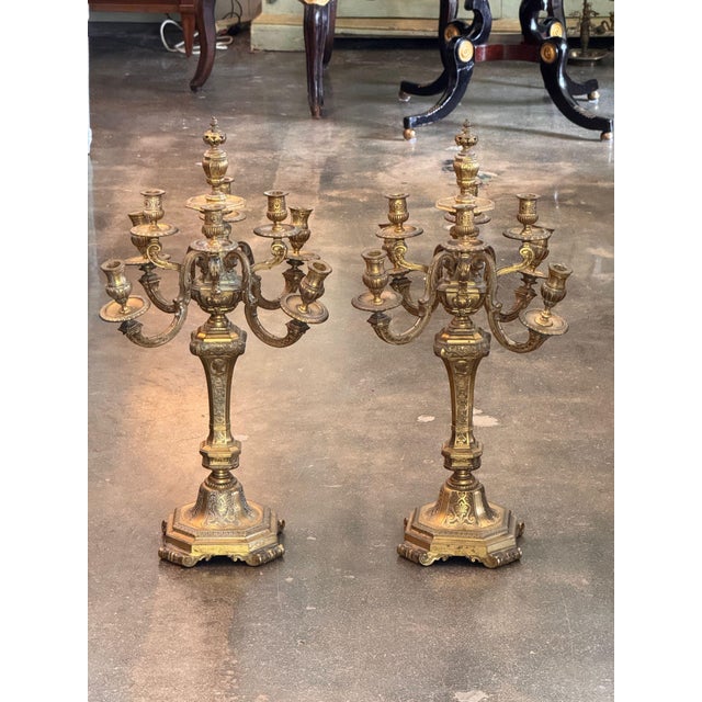 A pair of gilt bronze candelabra, each with a central urn issuing four scrolling arms with gadrooned drip pans and fluted...
