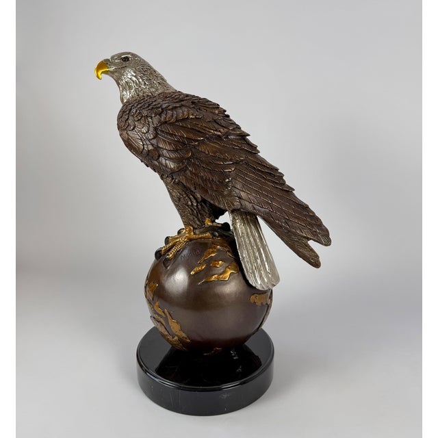 This bronze sculpture depicts a majestic bald eagle perched atop a globe, an enduring symbol of strength, freedom, and...