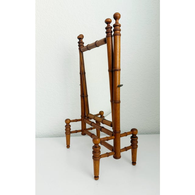 A stately faux bamboo tabletop or vanity mirror, crafted during the late 19th-century Victorian era. Features a finely...