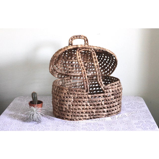 An unusual basket with handles that fit through a removable lid. Open weave with a large size and very sound. I cannot...