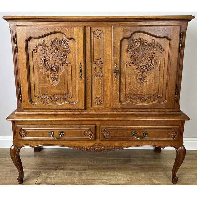 This elegant Vintage French Louis sideboard cabinet showcases beautifully carved oak doors, graceful cabriole legs, and...