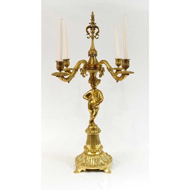 A striking pair of french gilt bronze candelabra, richly cast and centred around elegant figural supports in the...