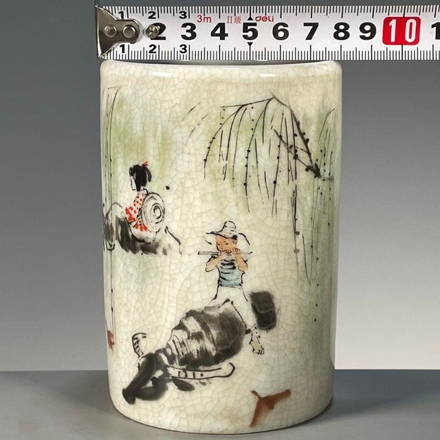 A charming Chinese porcelain brush pot (bitong) featuring a creamy, all-over crackle glaze. The cylindrical vessel is...