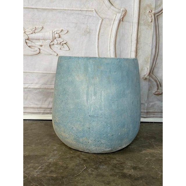 A beautifully understated terracotta planter featuring a clean, rounded silhouette and a softly weathered blue-gray...