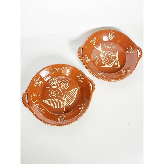 Charming pair of French glazed pottery dishes featuring a warm terracotta-colored ground decorated with contrasting white...
