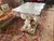 Shell encrusted table with marble top. Shells have been applied to wood finish of table. Marble top rests on base.