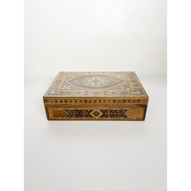 Large decorative wooden box dating from the 1970s, distinguished by its elaborate geometric marquetry decoration. The...