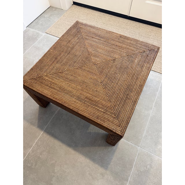 Vintage woven rattan square coffee table featuring a striking geometric paneled top and substantial architectural form....
