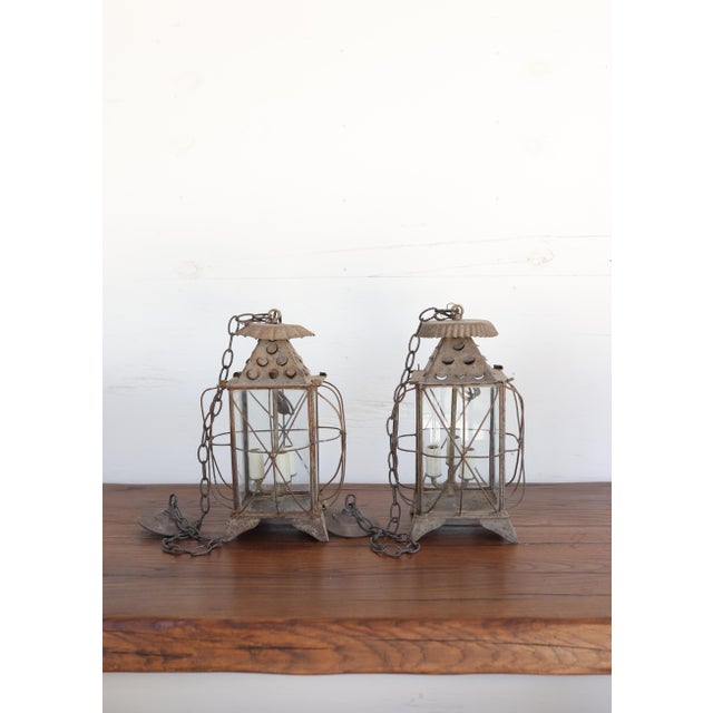 A charming pair of antique lanterns from the South of France, crafted in hand-riveted tôle with original glass panels and...