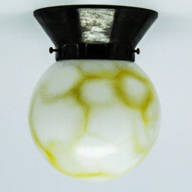 The pendant lamp was produced in the 50s. It is made in the art deco style. The construction is ebonite, glass lampshade....