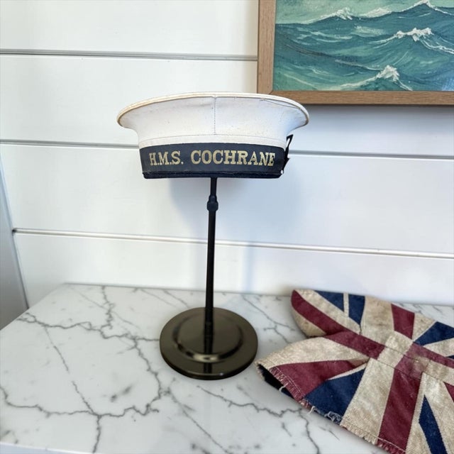 An authentic Royal Navy sailor’s cap bearing its original gilt-lettered H.M.S. COCHRANE tally band, offering a wonderful...