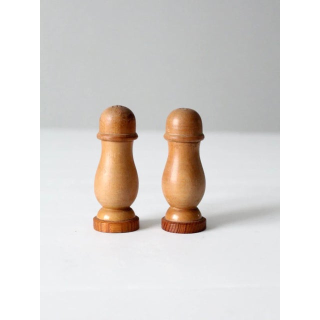 This is a pair of vintage wooden salt and pepper shakers, circa mid-20th century. The wooden shakers feature a smooth...