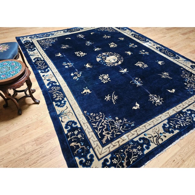 A graceful 19th century Chinese Art Deco rug in a near-square room-size format, featuring a deep navy blue field of...