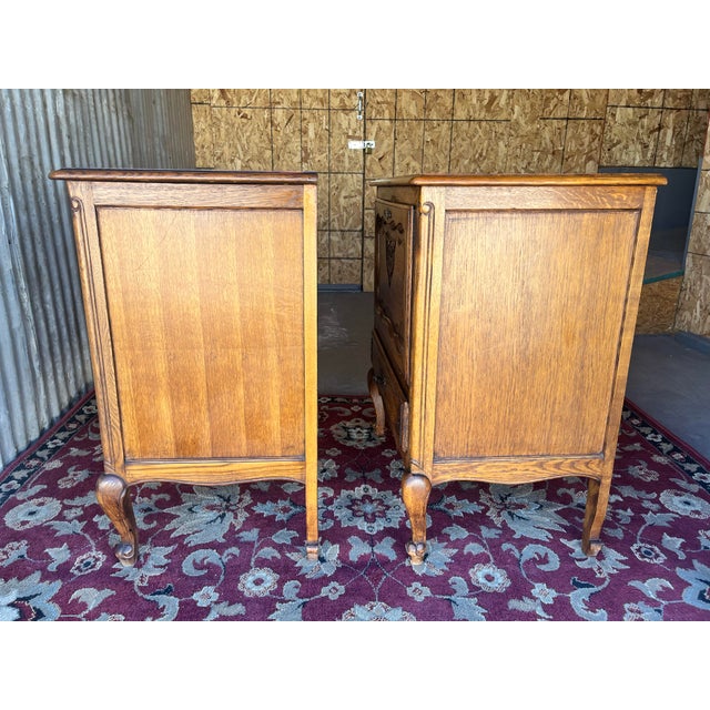 A distinctive matched pair of vintage French Louis XV-style oak bedside cabinets featuring beautifully figured wood,...