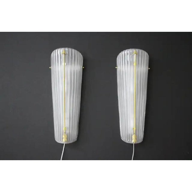 This pair of wall lights is very unusual with its nicely frosted white glass and its beautiful brass arrow which runs the...