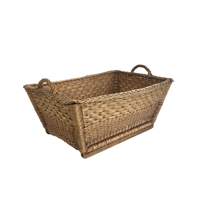 Traditional 1960s woven wicker French market basket with handles and braided trim. Two wood supports on the bottom extend...