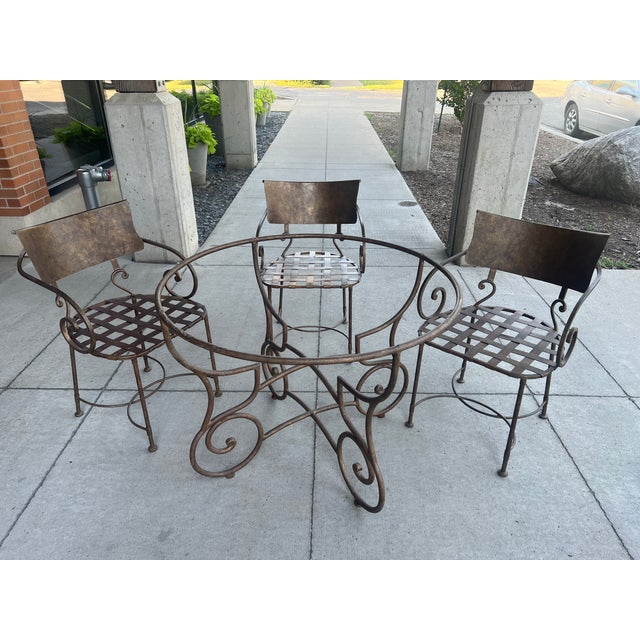 Three vintage wrought iron metal garden dining armchairs, featuring a bronze/gold finish, elegant scroll arms, lattice...