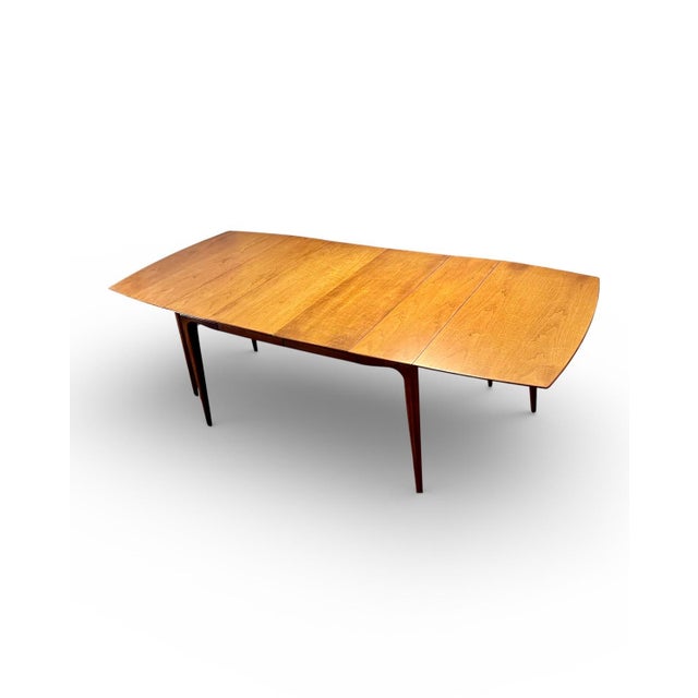This mid-century modern walnut dining table “the Watertown slide,” is a refined example of postwar American design,...