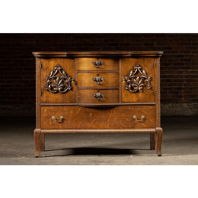 Early 20th-century bow-front serving cabinet constructed of richly figured oak with three central drawers, two flanking...