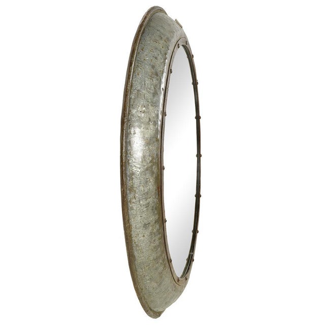 Large round mirror with a distinctly industrial character, composed of a wide, patinated metal frame punctuated by a...