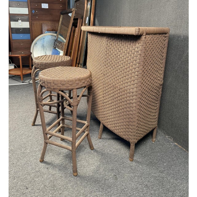 Modern Woven Outdoor Bar Set. Featuring a faux wicker weave throughout, (2) stools, and shelving for storage. Sturdy metal...