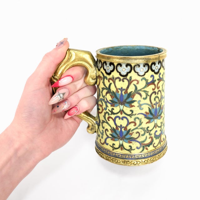 A fine antique Chinese cloisonne enamel tankard. In a tapering cylindrical form with an ear-shaped gilt bronze handle. The...