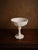 A lovely vintage milk glass compote with beautiful embossed detail, circa 1950s–60s. The wide scalloped bowl features...