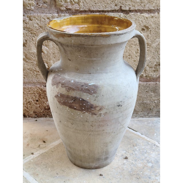 Antique terracotta jar with two handles and a honey-yellow glazed interior, typical of southern Italian country homes....