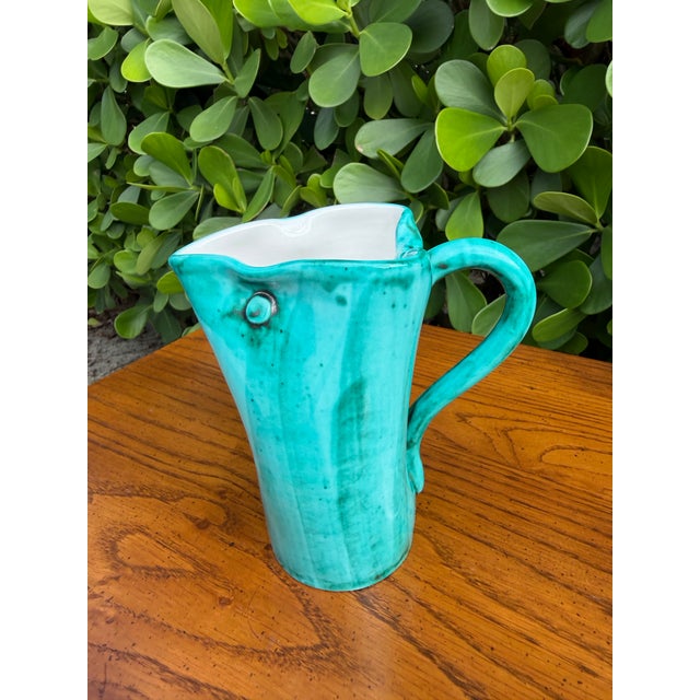 A sculptural mid-century Italian art pottery vessel featuring a vibrant turquoise glaze and distinctive organic form. The...