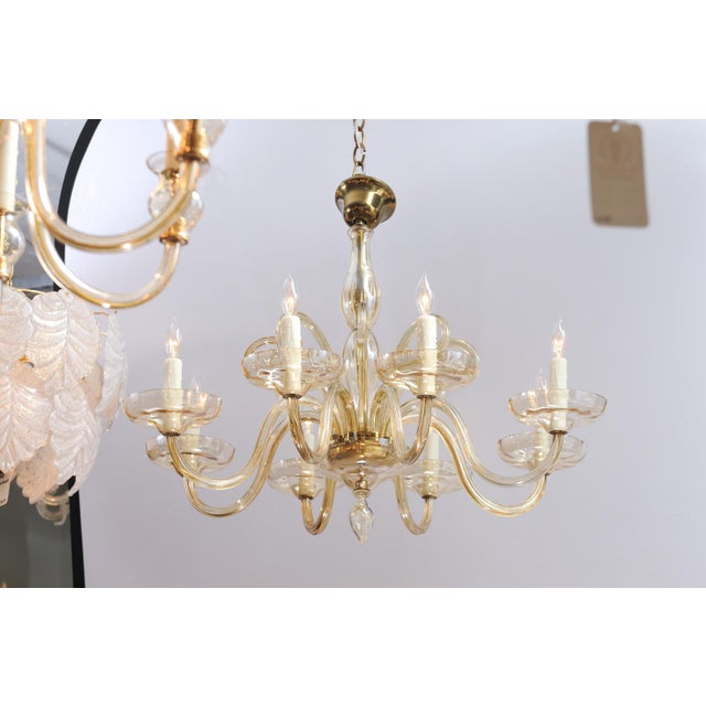 A sculptural Murano chandelier with amber glass arms, hand blown bobeche, and elegant fluted up-arms in between each of...
