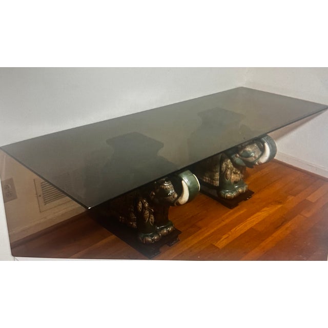 This coffee table features a distinctive design with elephant bases, which draws inspiration from Asian art and culture....