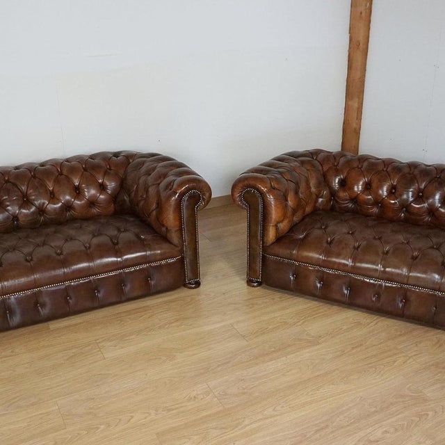 A pair of early 20th century small proportioned chesterfield sofas. Original and restored leather upholstery. Excellent...