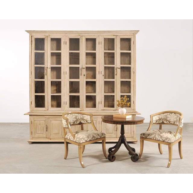 A monumental 19th century French Country-provincial style two-piece oak bibliotheque bookcase featuring a beautifully...