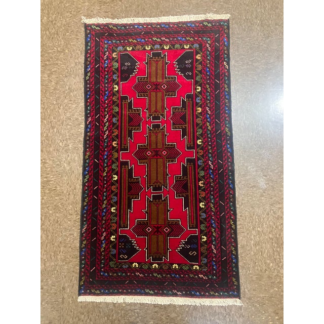 Hand-knotted Baluch rug, traditionally woven by tribal groups of eastern Iran and Afghanistan. Features a vivid red field...