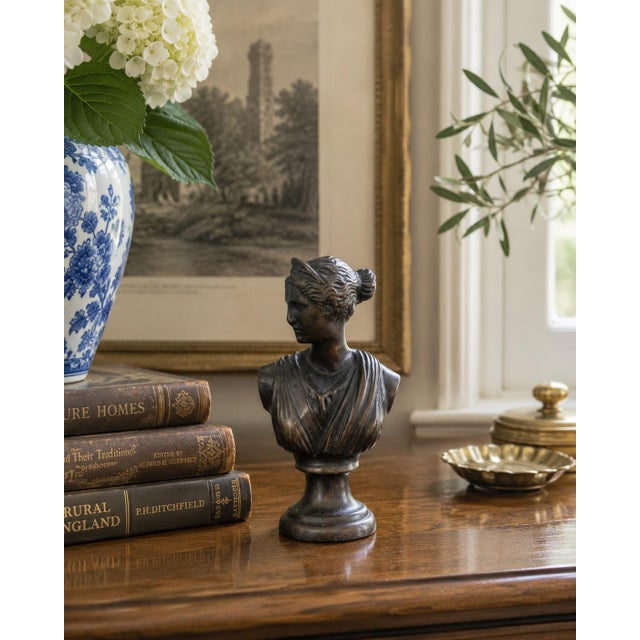 A handsome neoclassical bust depicting Diana the Huntress, rendered in cast metal with a dark, softly burnished finish...