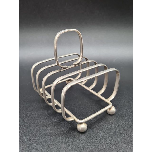 An elegant, silver-plated toast rack made in england. A classic model with five compartments and a convenient carrying...