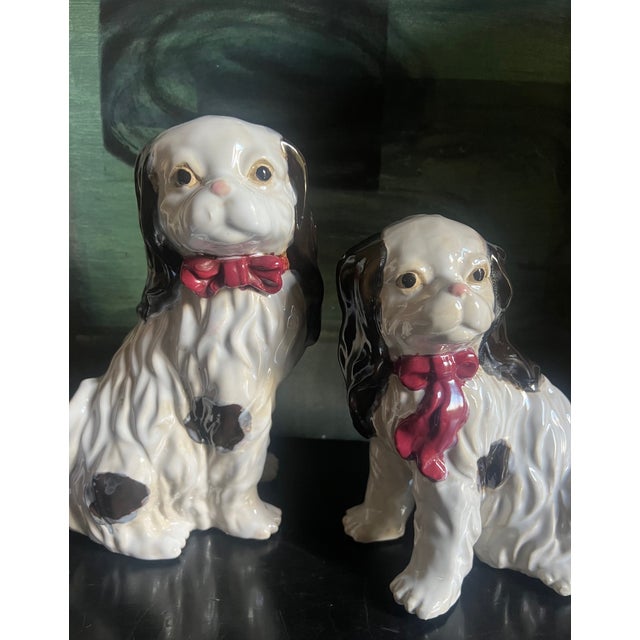 A pair of mid-century King Charles retrievers , spotted with maroon colored bows.
