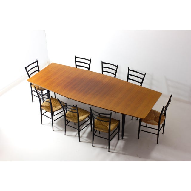 Large dining table, Belgium, 1960s. Teak veneer top with a subtly boat-shaped outline and rounded corners, resting on four...